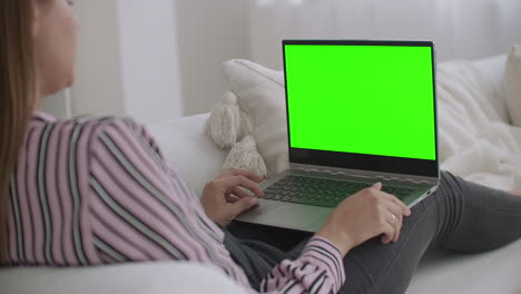 young-relaxed-woman-is-using-laptop-with-green-screen-for-chroma-key-technology-for-chatting-in-internet-calling-by-video-chat